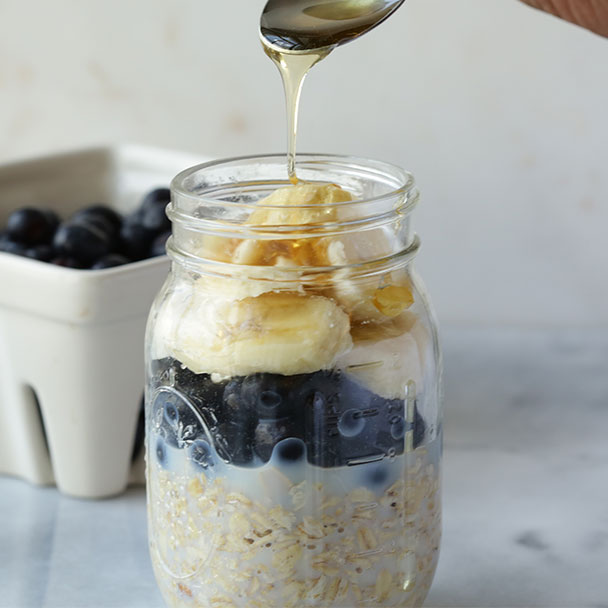 blueberry banana overnight oats topped with a drizzle of honey