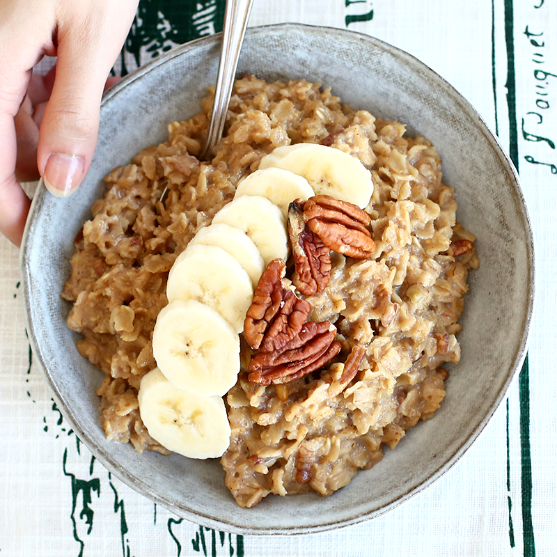 Quaker oats porridge topped with slices of banana and pecan nuts in a bowl