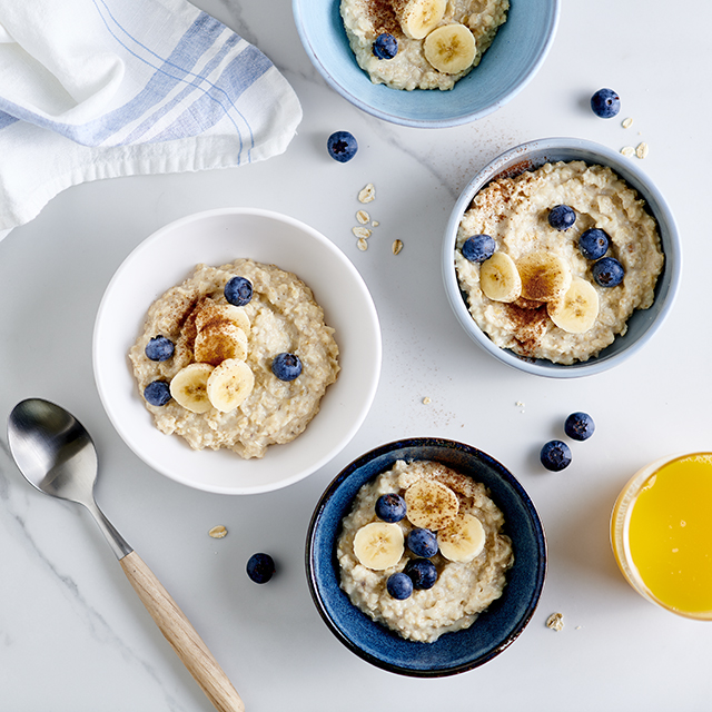 porridge in a bowl with chopped bananas and blueberries sprinkled on top