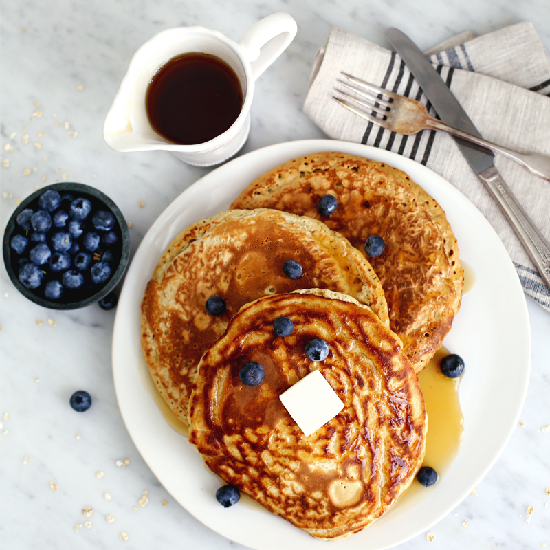 apple and oat pancakes on a plate with blueberries and compote