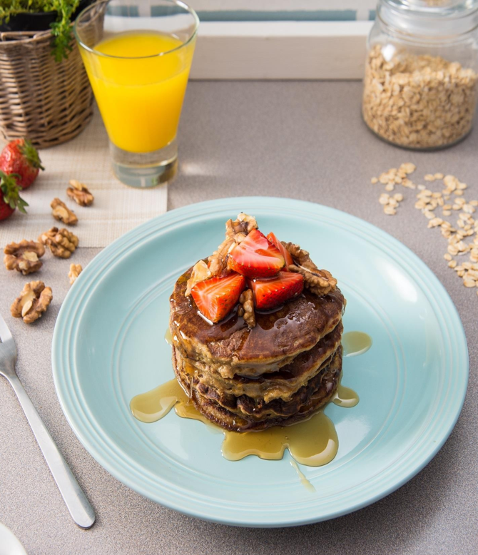 stacked super pancakes served with strawberries, walnuts and maple syrup