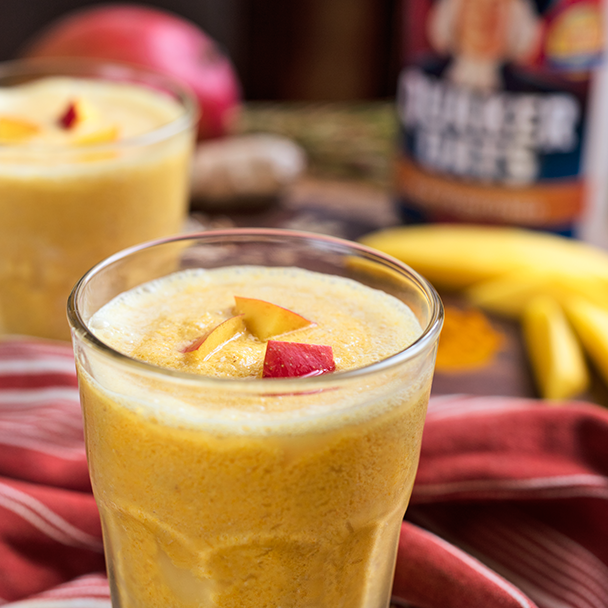 cup of coconut mango turmeric oat smoothie with sliced mango on top